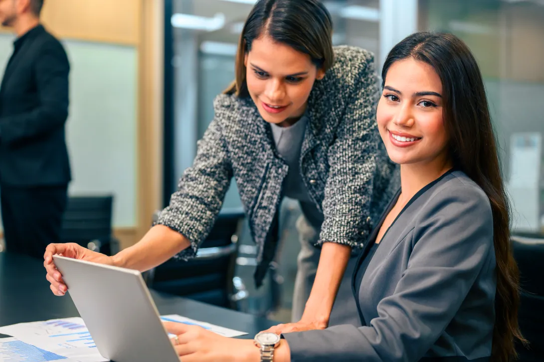 Colaboradoras revisando información en una computadora portátil durante una reunión de trabajo