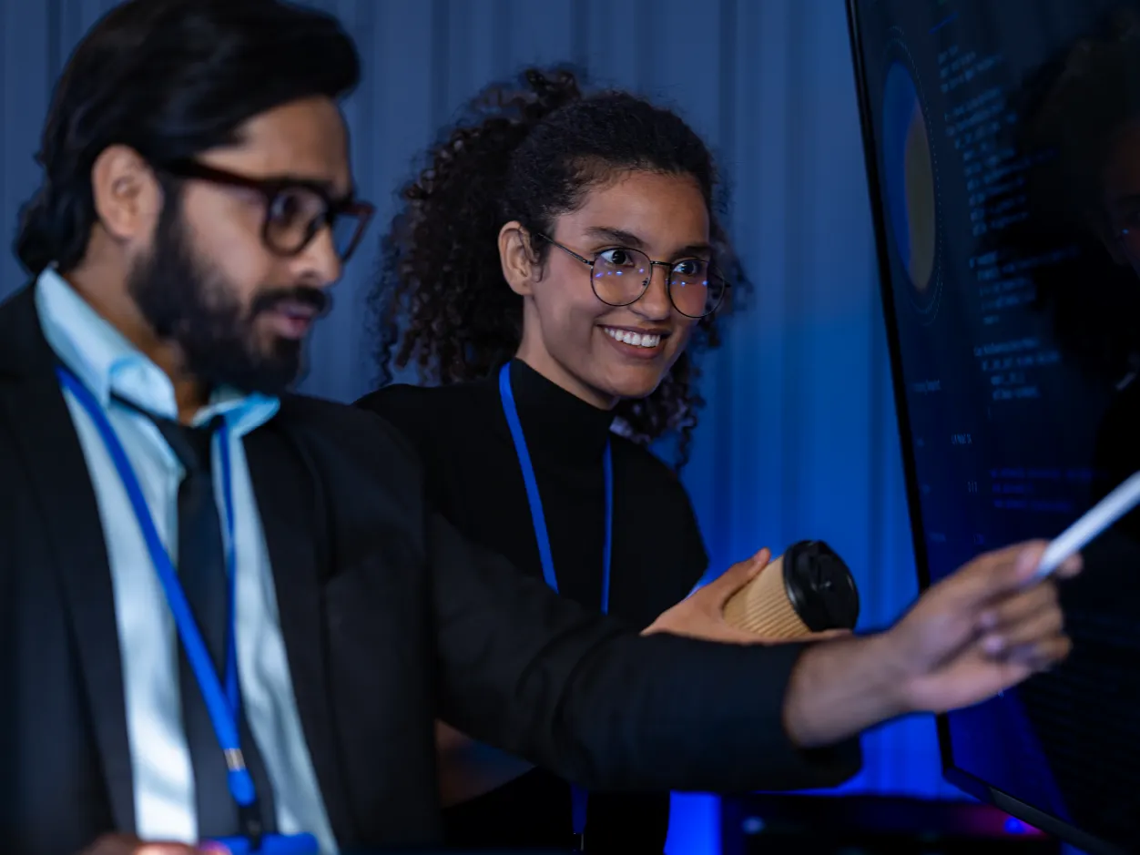 Mujer sonriendo frente a una computadora en un entorno de oficina con iluminación cálida, representando el uso de los beneficios asociados a nómina BCR.