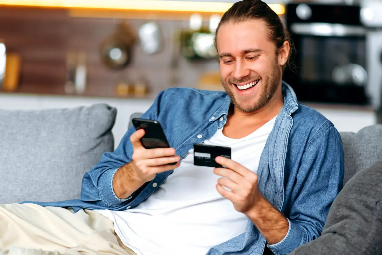 hombre feliz con telefono y tarjeta en mano