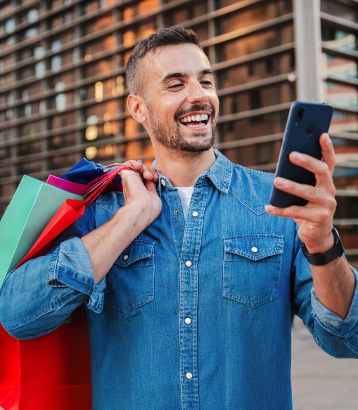 Hombre sujetando sus compras y viendo su celular