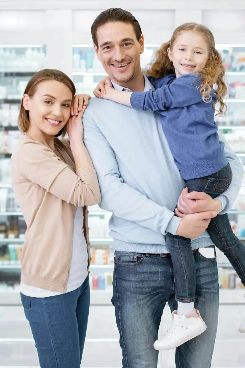Pareja feliz junto a su hija comprando medicamentos en una farmacia